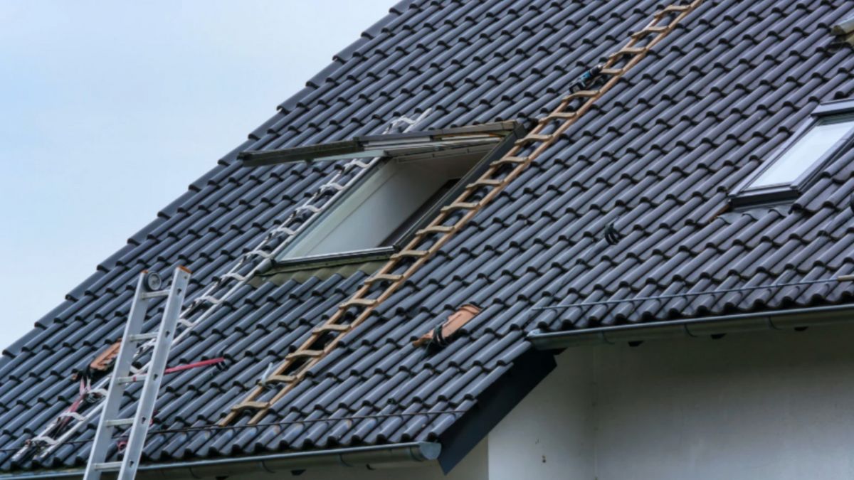 A roof with a skylight and ladders set up, showing a typical residential project where hiring a qualified roofing contractor is important.