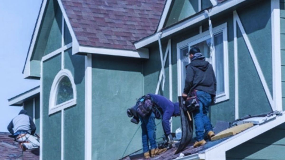 Three men engaged in roof repair work on a house, highlighting dependable roofing services.