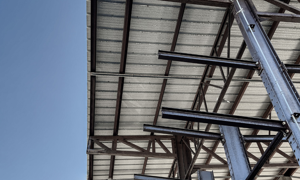 Underside view of a commercial roof structure showing roofing materials and support framing.