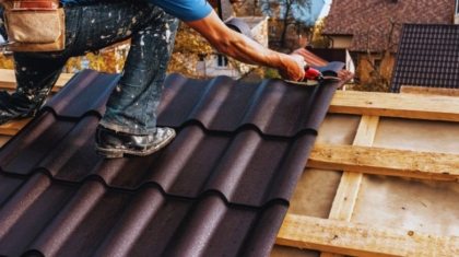 Roof installation in Ridgeland showing a contractor securing metal roofing panels on a residential home using professional tools and safety gear.