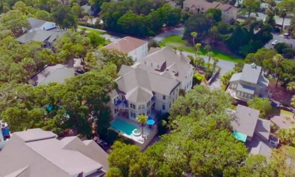 Aerial view of luxury homes and tree-lined streets in North Forest Beach, Hilton Head Island, featuring spacious residences with private pools and lush coastal landscaping.
