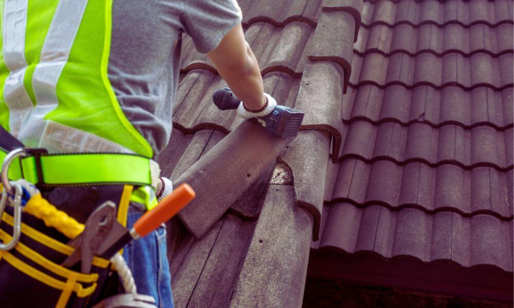 Roofer in safety gear repairing clay tile roof on a home in North Forest Beach, Hilton Head Island.
