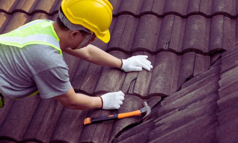 Roofing contractor in safety gear repairing damaged shingles on a residential roof in Shipyard Plantation, Hilton Head Island.