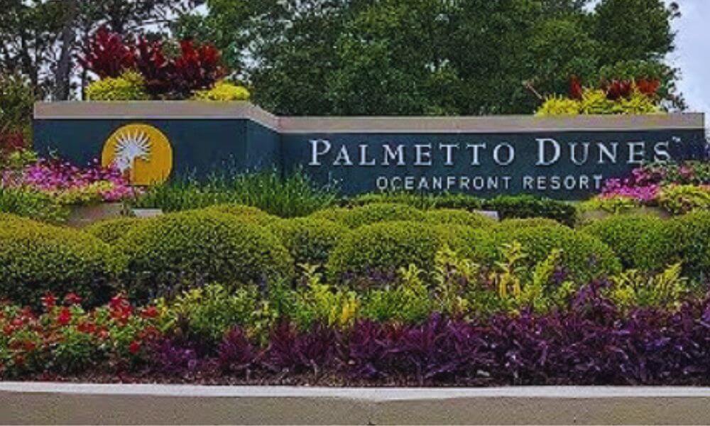 Entrance sign for Palmetto Dunes Oceanfront Resort surrounded by lush landscaping and colorful flowers on Hilton Head Island.