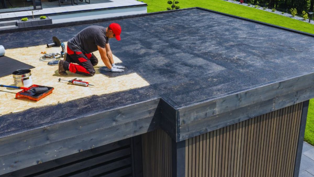 Contractor performing flat roof repair on a residential building by installing roofing membrane in Hilton Head Island, SC.