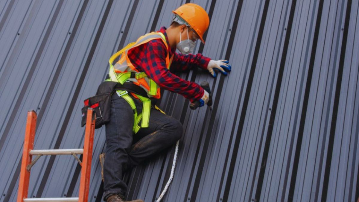 Roofing contractor installing a standing seam metal roof while using safety gear, highlighting professional metal roofing services from a metal roofing company in Hilton Head, SC.